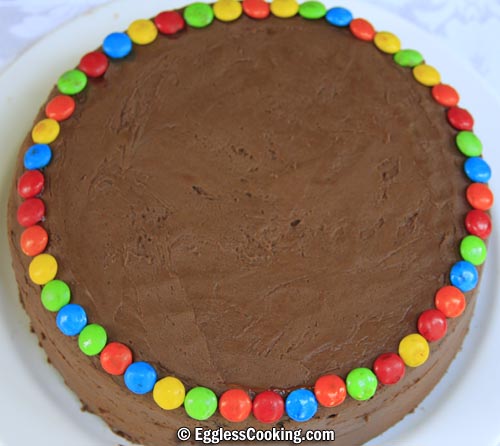 Arrange M&Ms around the circumference of the top-level cake.