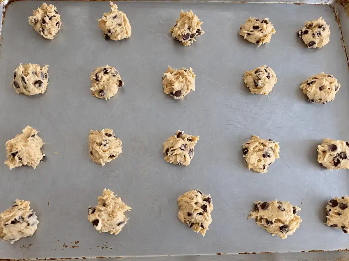 Scoops of eggless chocolate chip cookie dough spaced apart on a baking sheet