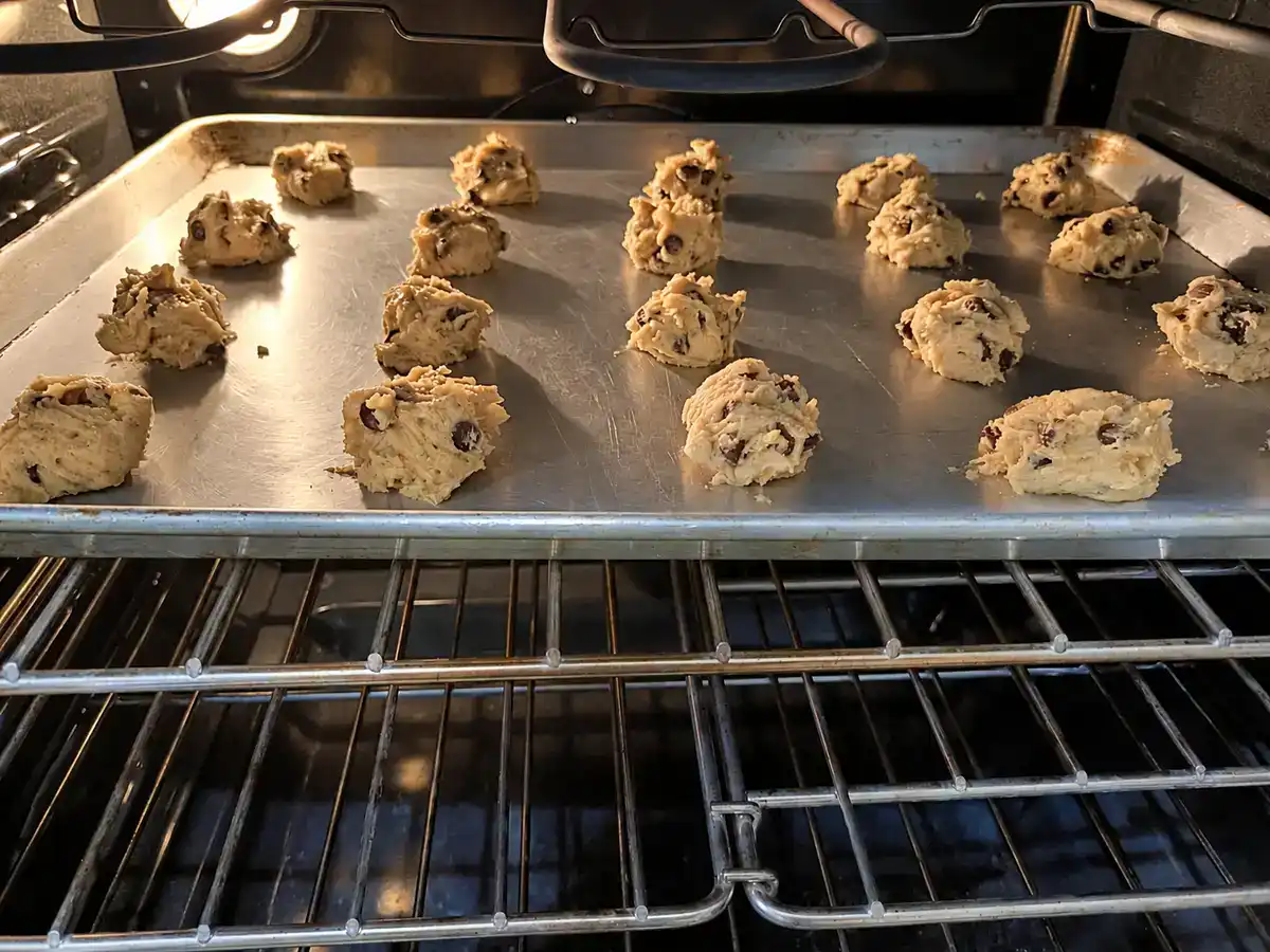 Eggless chocolate chip cookies baking on a sheet pan in the oven