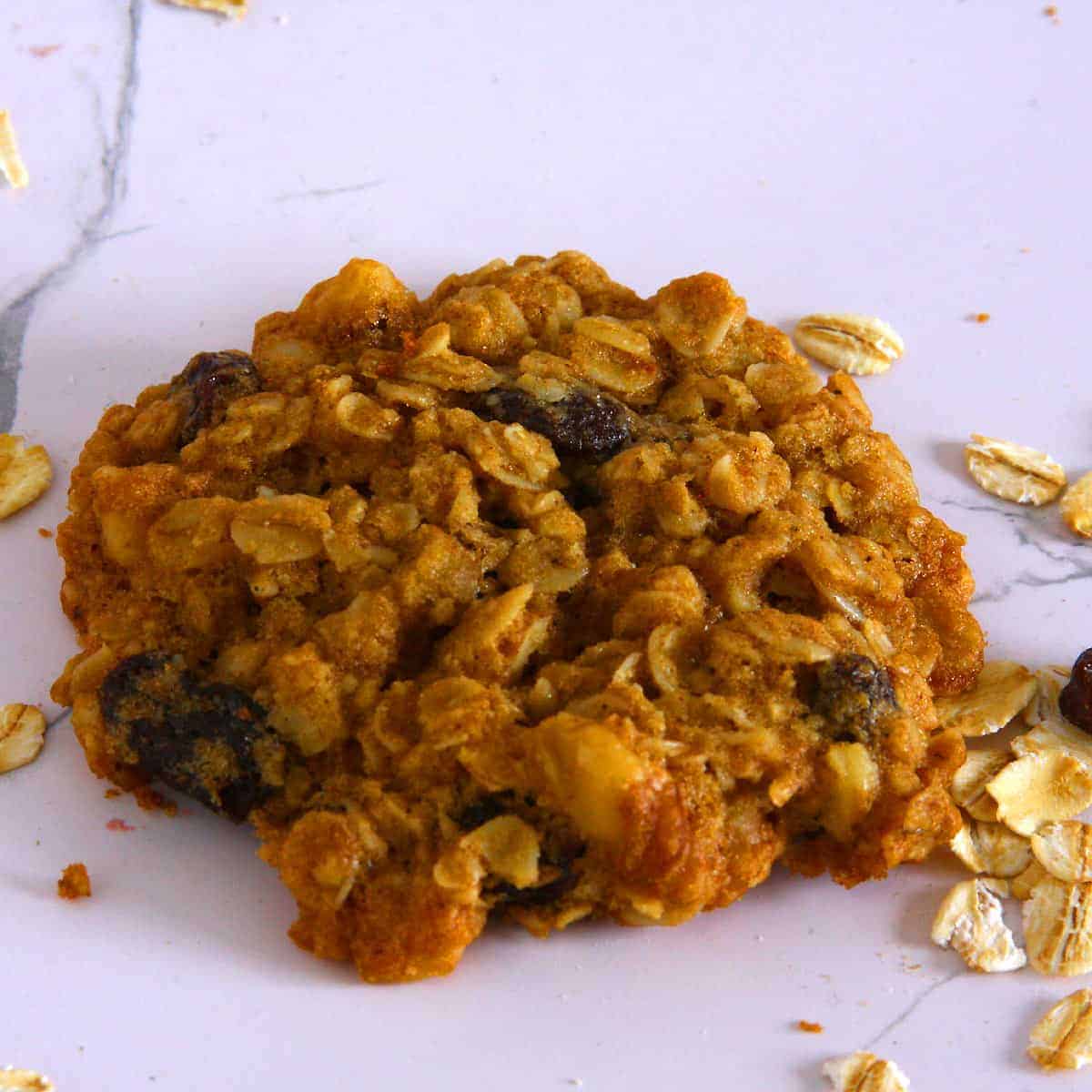 Freshly baked vegan oatmeal raisin cookies served on a plate, ready to enjoy with scattered rolled oats and raisins.