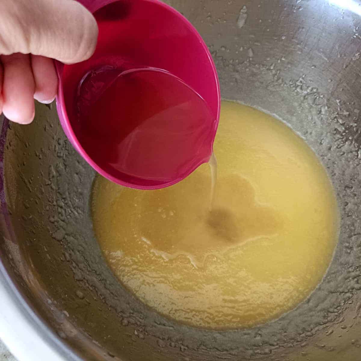 Aquafaba and vanilla extract are poured into the creamed mixture to replace eggs and add flavor.