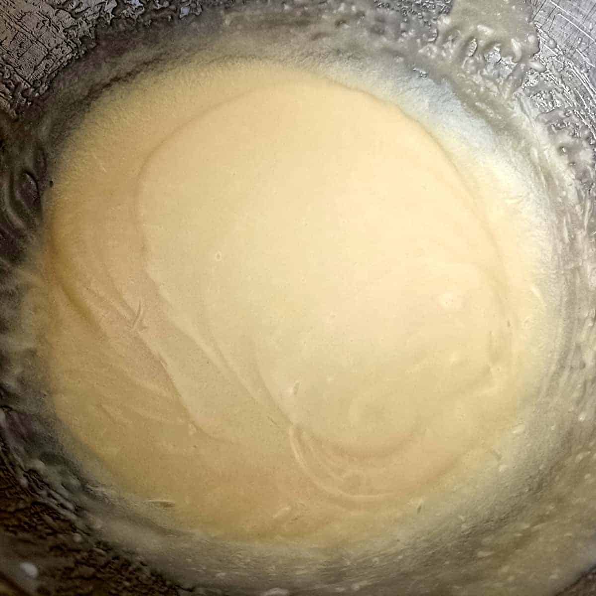 The wet mixture is beaten until pale, silky, and fully emulsified.