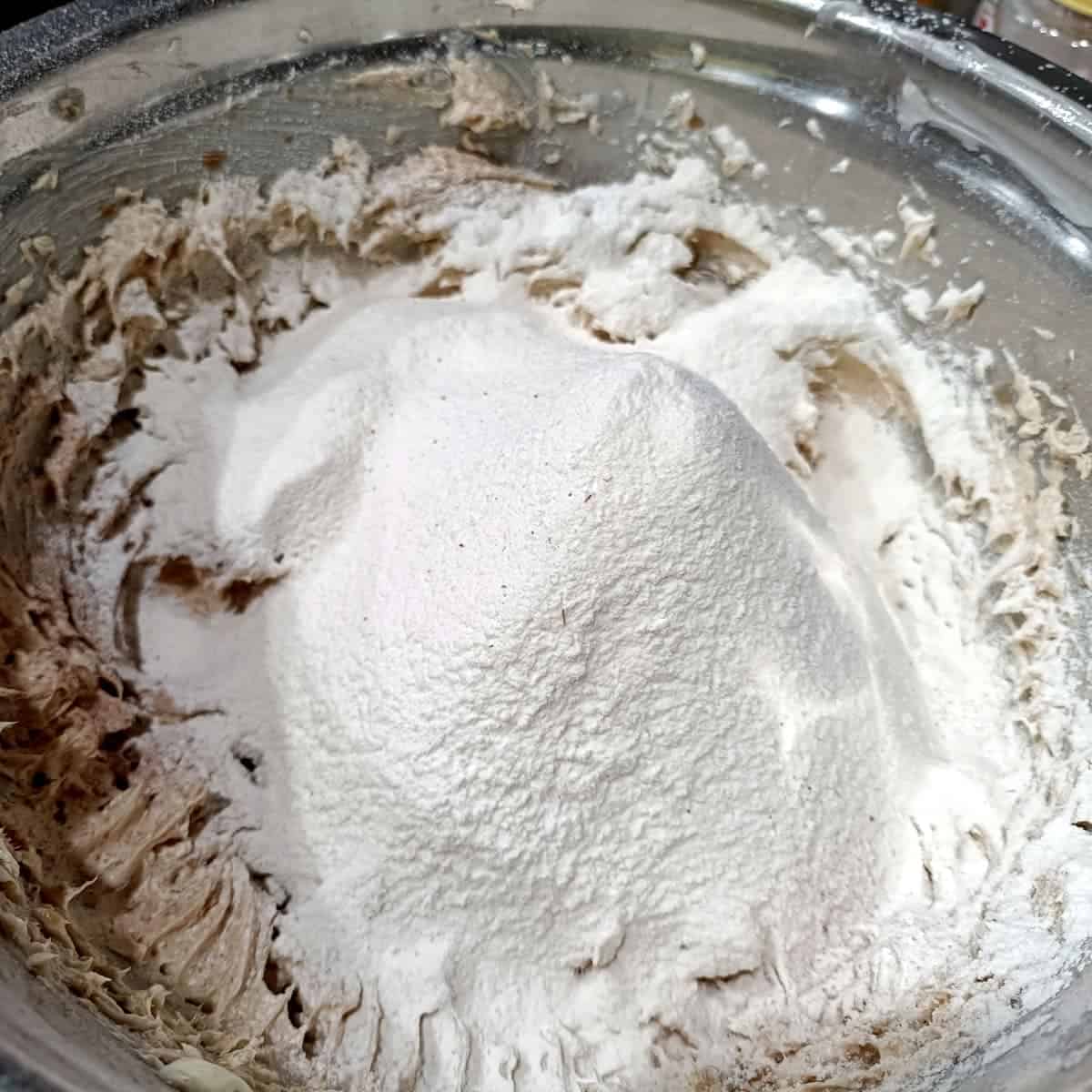 Combine wet and dry: The sifted dry ingredients are added to the wet mixture in the bowl.