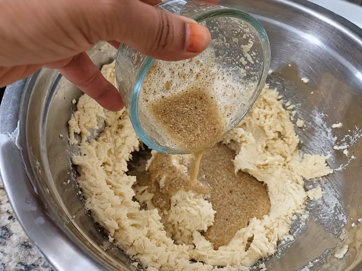 Prepared flax egg being poured into the creamed butter and sugar mixture