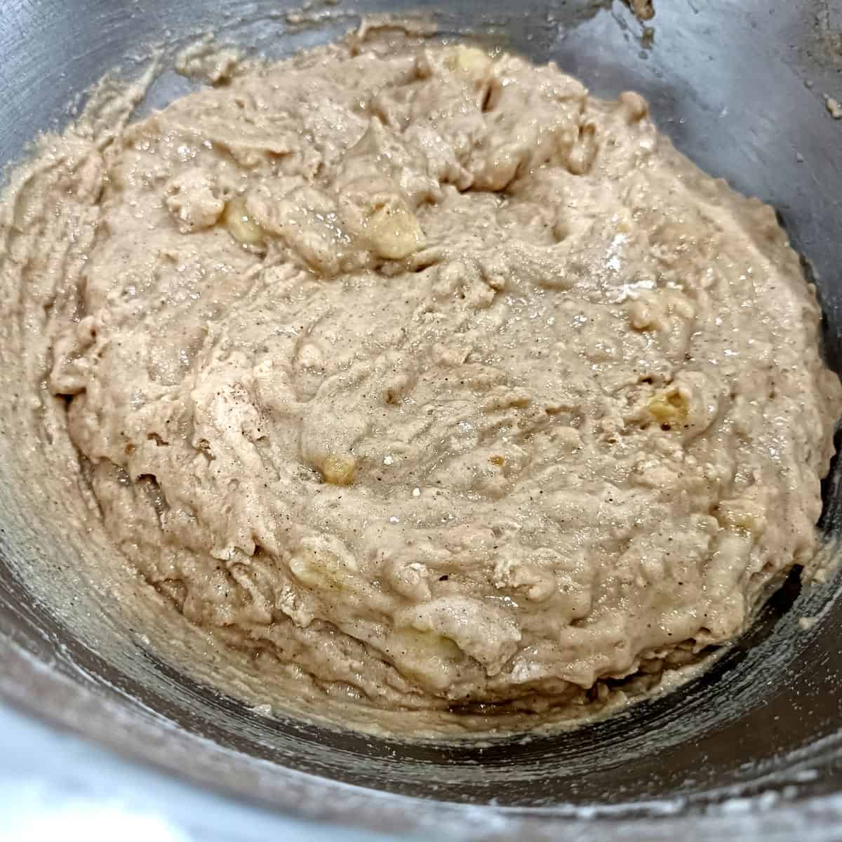 Thick vegan banana muffin batter mixed just until combined with small banana pieces visible