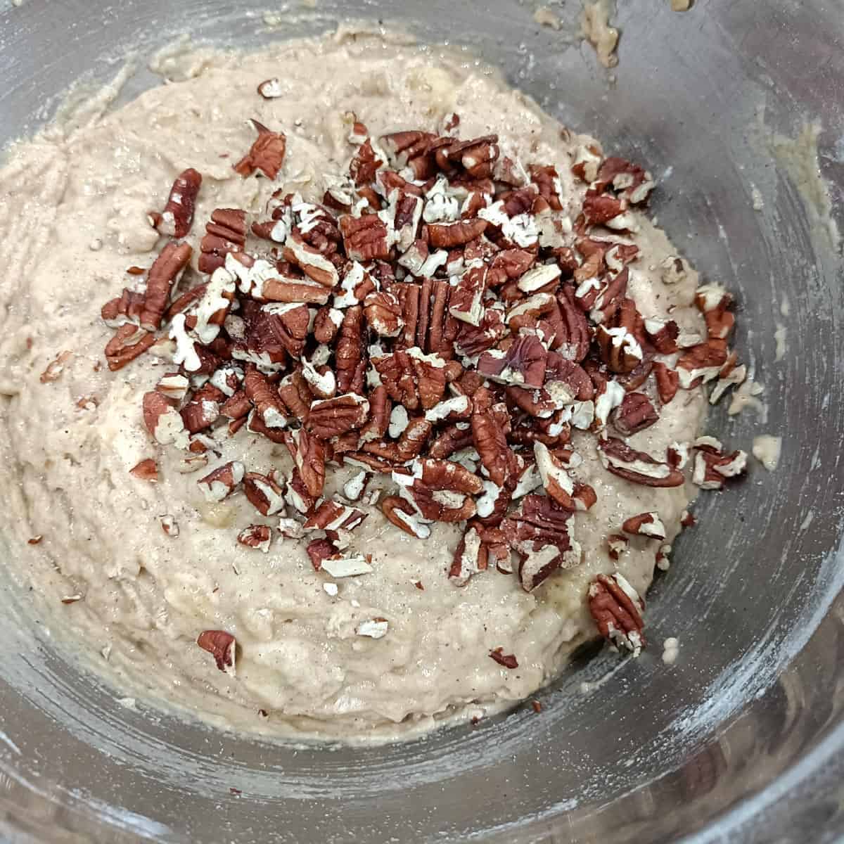 Chopped pecans added to thick vegan banana muffin batter before folding