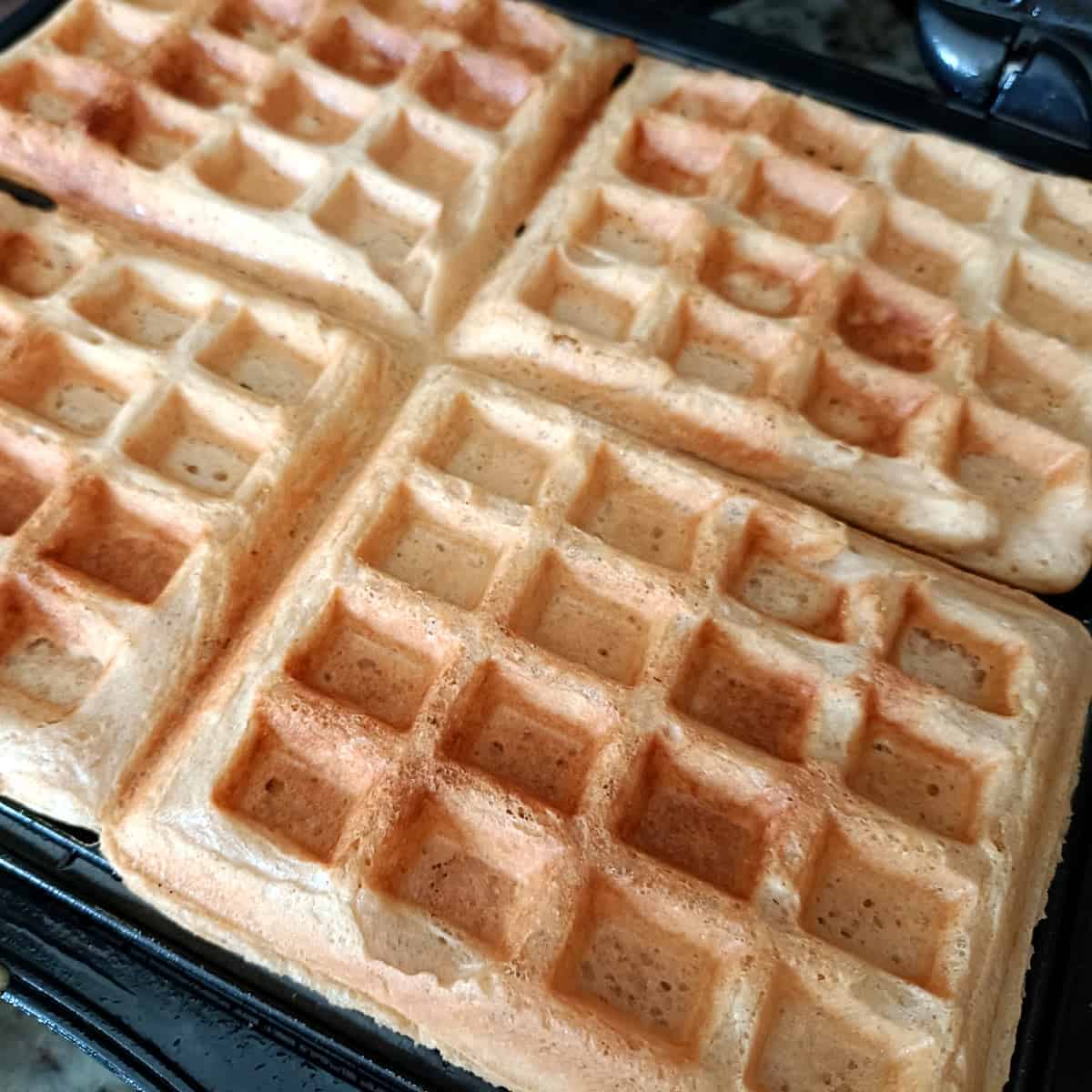 Golden brown eggless waffles cooked crisp in a waffle maker