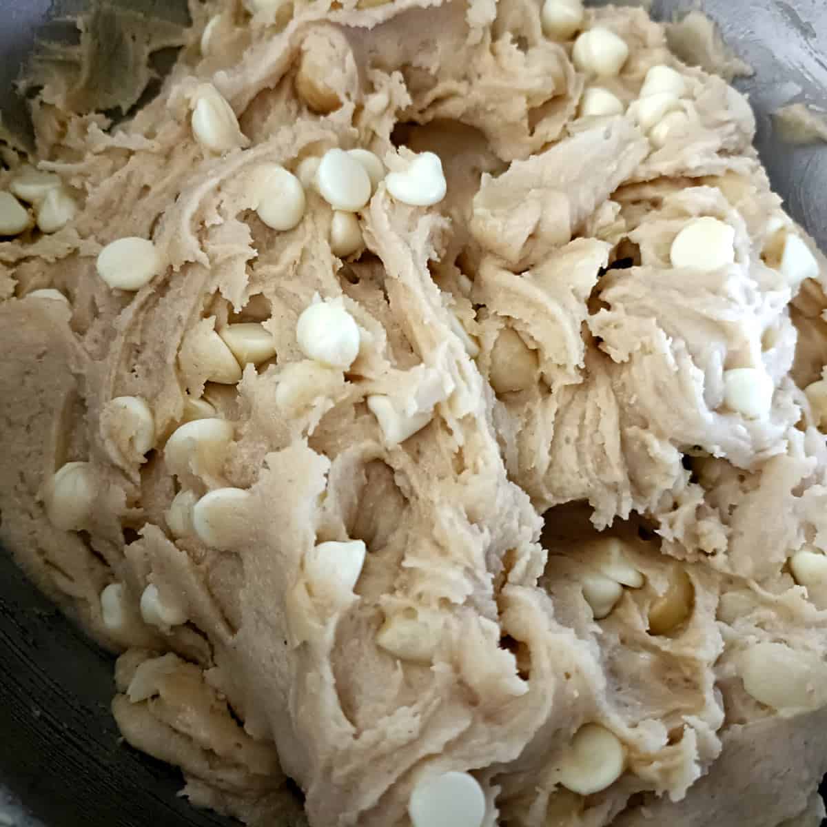 The finished cookie dough looks thick, creamy, and evenly studded with white chocolate and nuts.