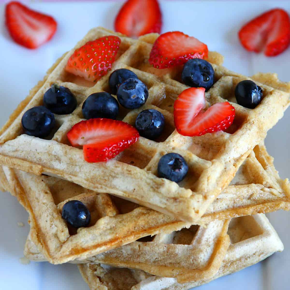 Eggless waffles topped with fresh strawberries and blueberries, served warm for breakfast.