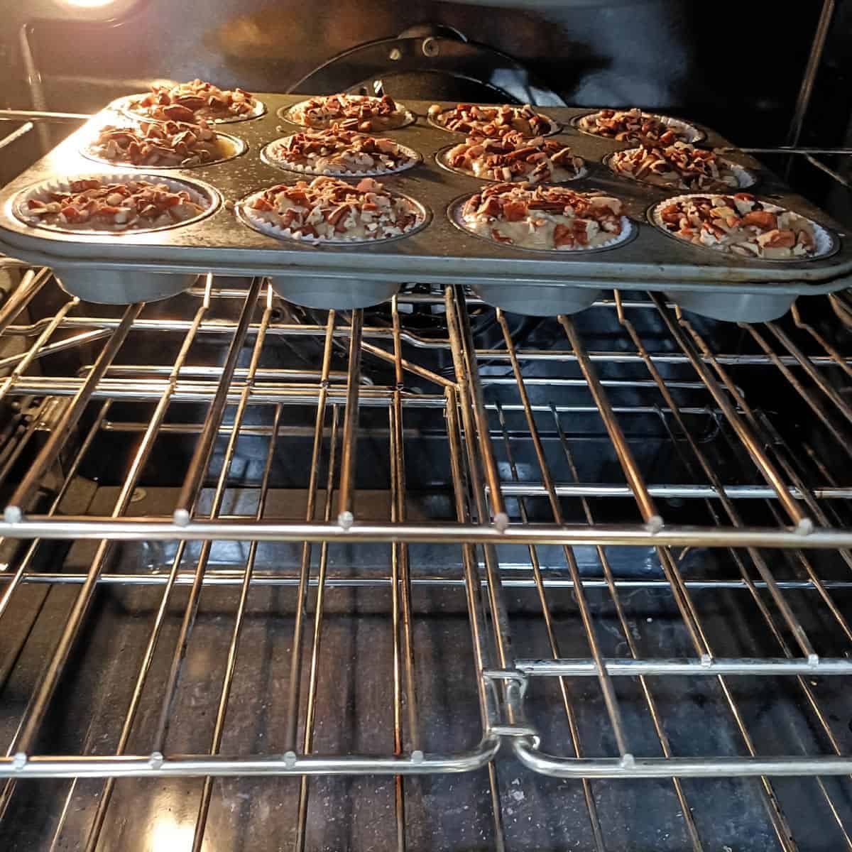 Vegan banana pecan muffins in a muffin pan baking on the center rack of an oven