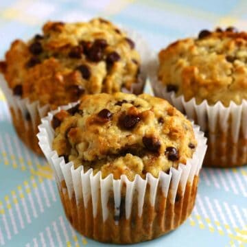 Eggless banana chocolate chip muffins with golden tops and melty chocolate chips in paper liners