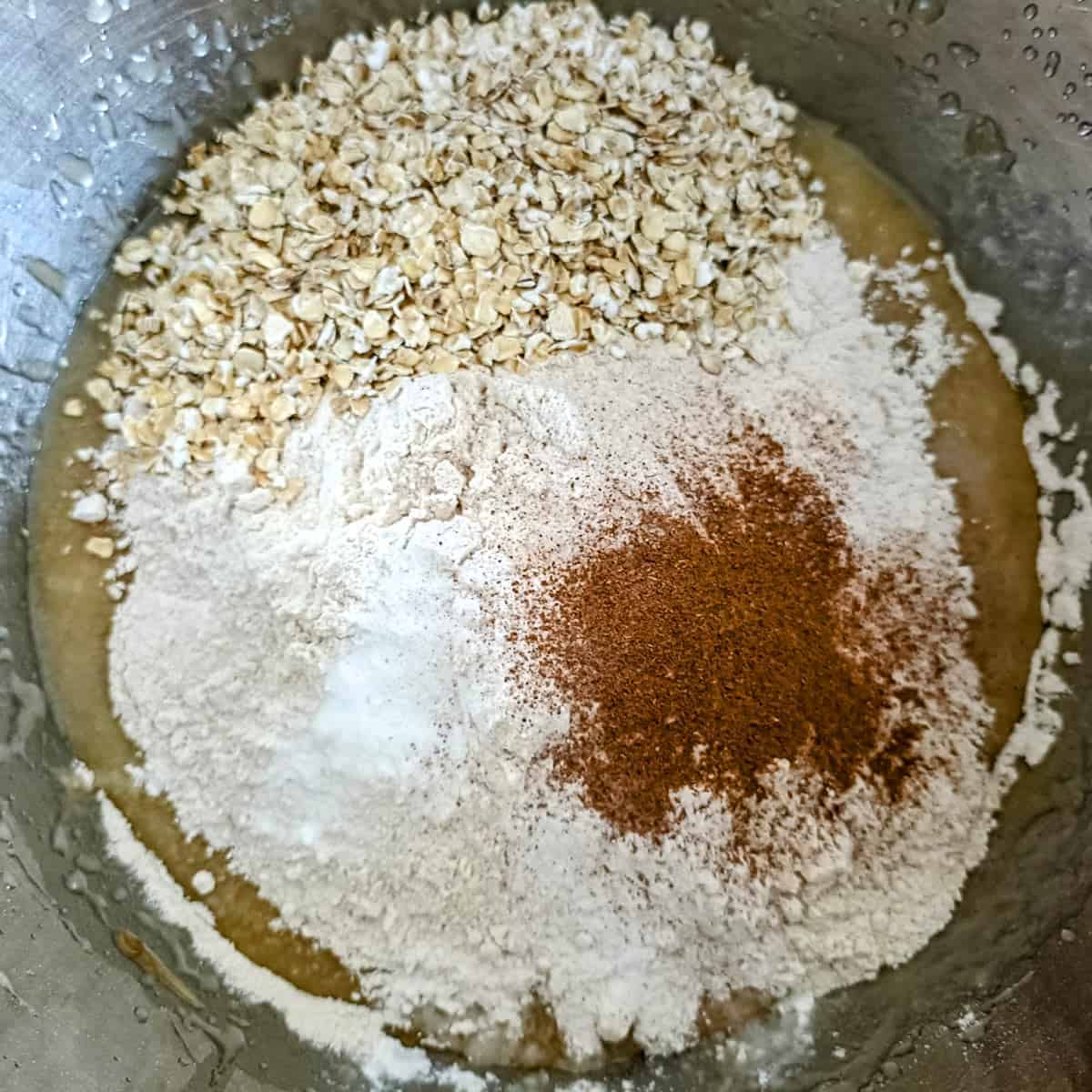 Adding flour, oats, cinnamon, baking powder and baking soda to banana mixture