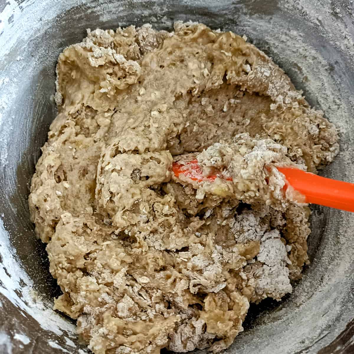 Mixing wet and dry ingredients into thick banana muffin batter