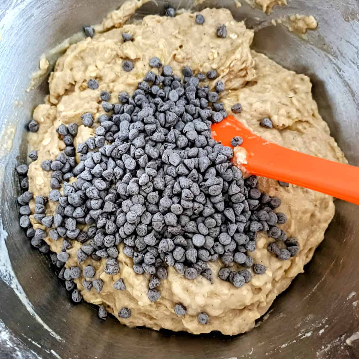 Adding chocolate chips to banana muffin batter before folding