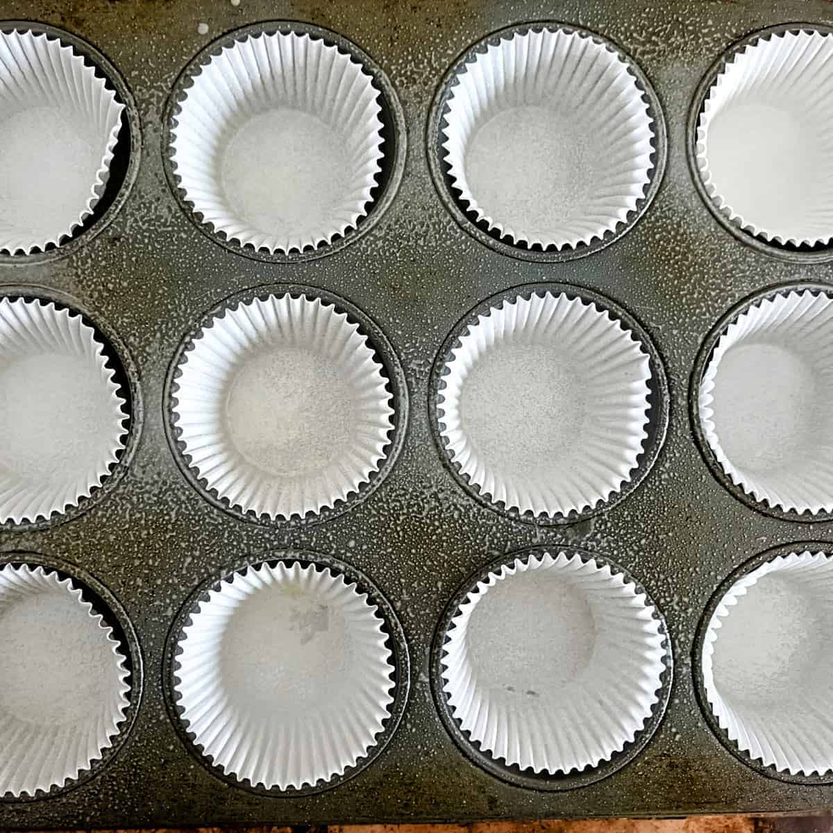 Muffin tray lined with paper liners and greased for baking