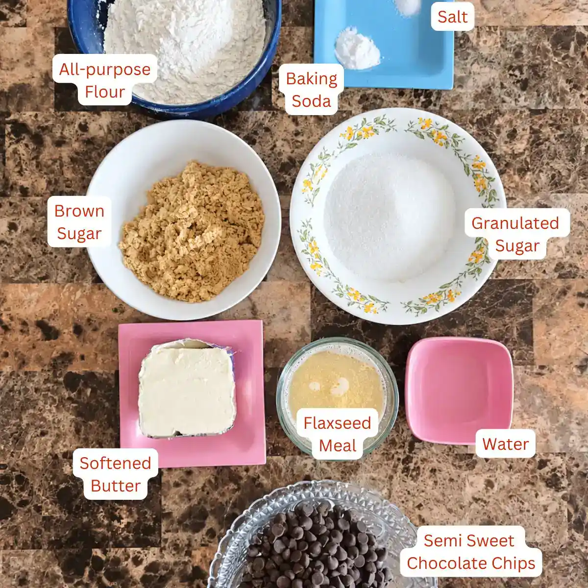 Ingredients for eggless chocolate chip cookies including flour, brown sugar, granulated sugar, butter, flaxseed meal, water, baking soda, salt, vanilla, and semisweet chocolate chips